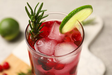 Tasty cranberry cocktail with rosemary and lime in glass on table, closeup