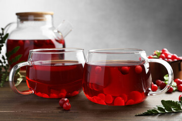 Tasty hot cranberry tea in glasses and fresh berries on wooden table