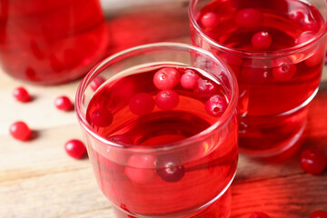 Tasty cranberry juice in glasses and fresh berries on wooden table, closeup