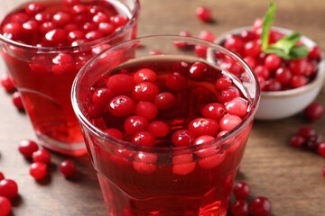 Tasty cranberry juice in glasses and fresh berries on wooden table, closeup