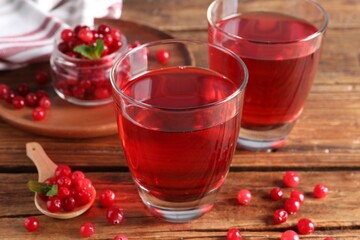 Tasty cranberry juice in glasses and fresh berries on wooden table, closeup