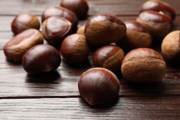Sweet fresh edible chestnuts on wooden table, closeup