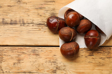 Fresh edible sweet chestnuts on wooden table, top view. Space for text