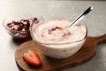 Tasty yoghurt with jam and strawberry on grey table, closeup