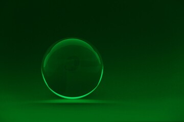 Transparent glass ball on dark green background. Space for text