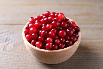 Fresh ripe cranberries in bowl on wooden table, closeup
