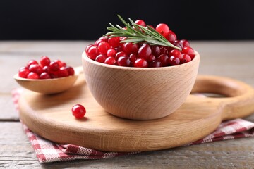 Fresh ripe cranberries and rosemary on wooden table