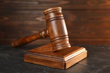 Wooden gavel and sound block on dark textured table, closeup