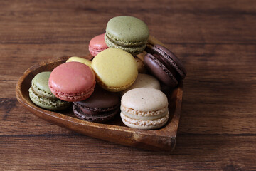 ハート型の木製ボウルにいれた様々な色のマカロン