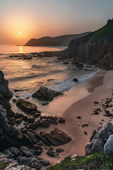 the sunset with a beach and rocks and cliffs