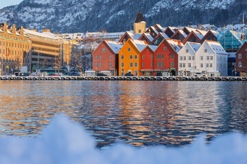 Bergen waterfront cityscape.with pucturesque bryggen houses in colorful theme in front of the wharf. Looking from across the bay on cold winter snow day.