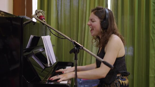 Beautiful western woman plays the piano and sings with emotion