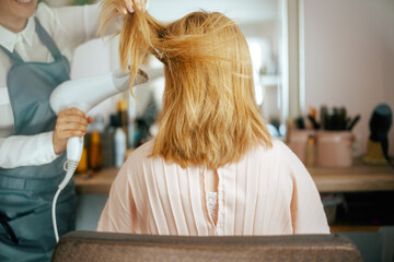 woman hairdresser in hair studio blowout hair with hair dryer