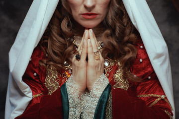 Closeup on medieval queen in red dress with veil praying