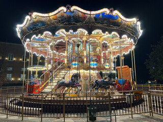 Capture the enchanting glow of a merry-go-round against the backdrop of the night sky, evoking a...