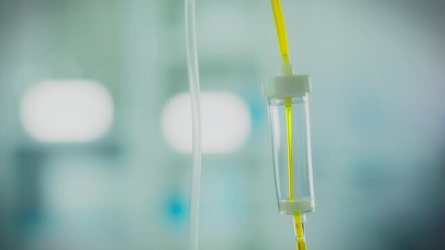 The transparent tube is filled with a bright yellow liquid, which under pressure forms a stream, flowing through the iv drip system. Medication infusion process