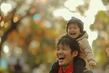 The image portrays a heartwarming moment of a joyful father carrying his happy child on his shoulders, both smiling broadly, set against a blurred autumnal background.
