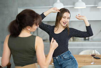 Fototapeta premium In cozy kitchen, two women happily move and spin to beat of dance music. Dynamic ending to friendly gatherings