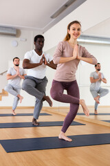 Obraz premium Young woman doing yoga postures on mat during group yoga training.
