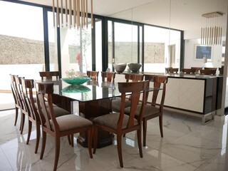 sillas de madera con una mesa de vidrio y un cuadro como decoración, con un espejo en el interior y con acabados de pintura blanca. 