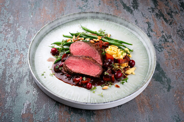 Obrazy na Plexi  Traditionally roasted saddle of venison fillet with spaetzle, beans and pine nuts in game sauce served as close-up on a Nordic Design plate