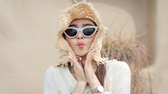Beautiful portrait brunette Asian woman wearing a fashionable white dress with modern sunglasses and a straw hat in a stylish dress and boots.