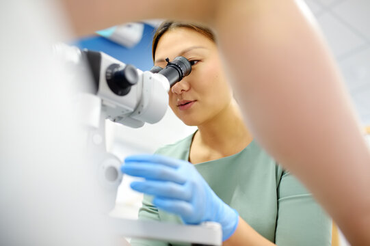 Gynecologist examines a patient using microscope in a gynecological chair. Doctor performs a colposcopy on a young girl in a modern medical office. Diagnosis of cervical cancer.