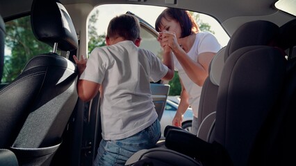 Mom gets her son out of car seat, safe car. Family road trip. Mom cares about her sons safety. Child sits in car child seat. Happy family. Mother secures her son in car seat using child safety belt.