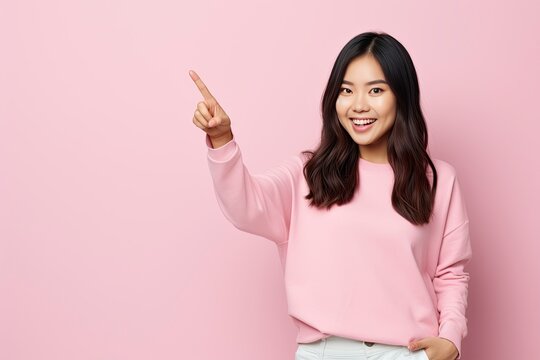 Happy young asian teen woman standing with her pointing finger aside. one color background, copy space - generative ai