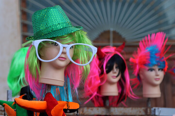 Mannequin heads with glasses, wigs and hats for carnival for sale at a street stall