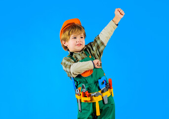 Little child in builders uniform and hard hat with toy tools. Kid playing with repair tools. Cute...