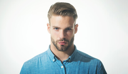 Closeup portrait of sexy fashionable bearded man in denim shirt. Handsome unshaven man with stylish hairstyle. Male fashion. Serious guy with beard and mustache in trendy denim shirt. Casual clothing.