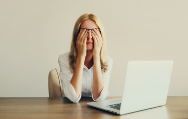 Tired overworked woman employee suffering from headache, rubbing eyes, working with laptop