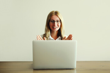 Woman working on laptop greets communicates with friends via video call