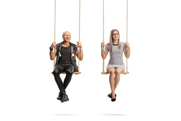 Punk and a young woman sitting on swings and looking at camera