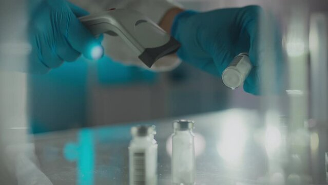 A laboratory researcher wearing nitrile gloves concentrates scanning drug data in a drug warehouse. Smooth movement young expert uses a laser scanner using modern technology