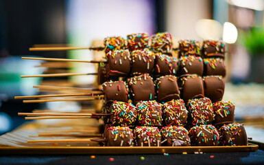 Pieces of fruit covered wirg chocolate and colorful sprinkles. 