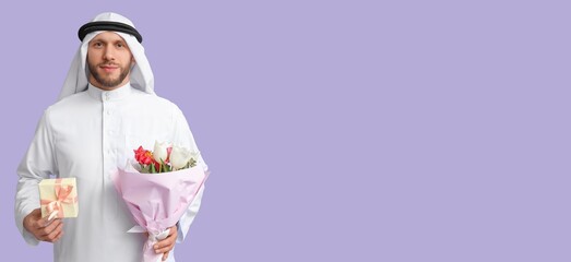 Young Arab man with flowers and gift on lilac background with space for text. International Women's Day