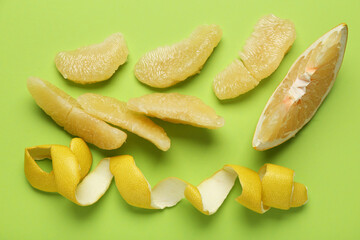 Pomelo fruit slices and peel on green background