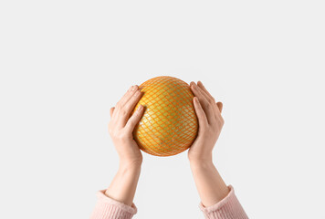 Female hands holding sweet pomelo in net on white background