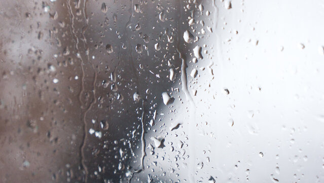 Macro of water drops on glass. Large rain drops strike window during winter shower. Pure rain drops.
