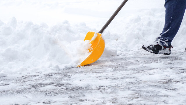 Man shoveling snow off of his driveway after a winter storm in Canada. Man with snow shovel cleans sidewalks in winter. Winter time.