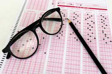 Optical reader, pencil, glasses, and eraser on it. Exam, idea conspet. Future Anxiety. Uncertainty. Multiple choice exam.Adults taking the exam.