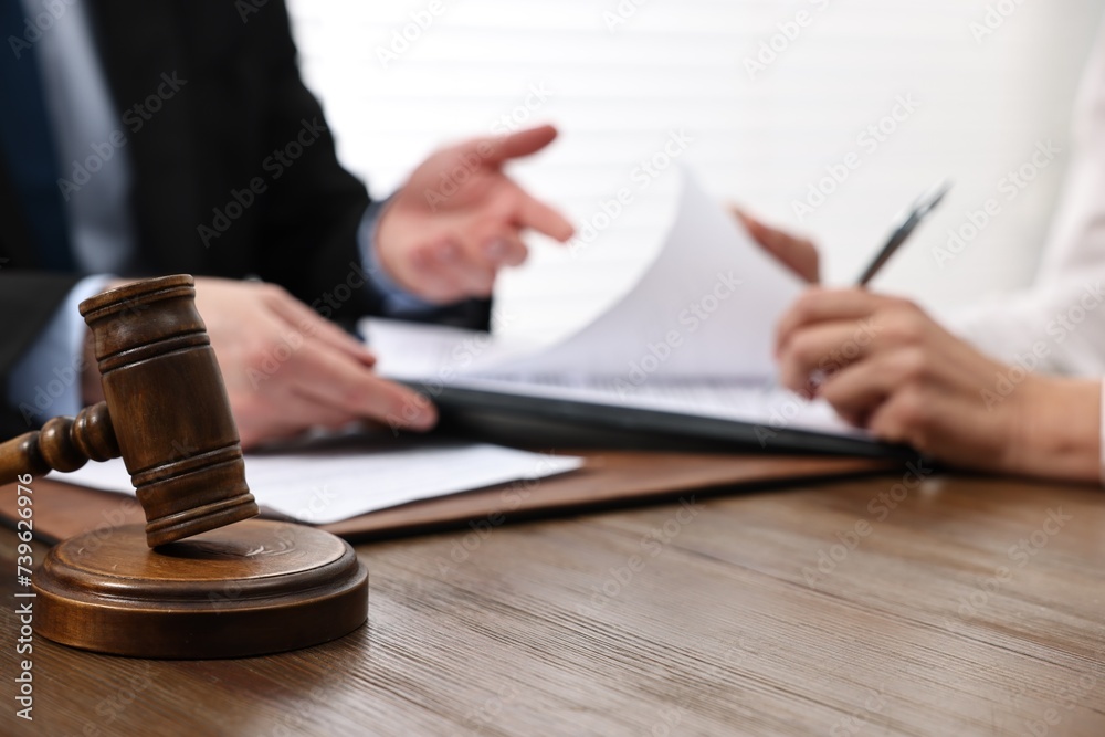 Wall mural Senior woman signing document in lawyer's office, focus on gavel