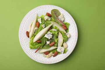 Delicious pear salad on green background, top view