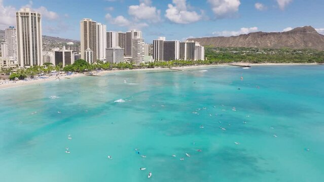 Scenic Diamond head volcano on sunny day. Hawaii vacation at Waikiki beach resorts panorama with blue waters. Aerial beach on tropical exotic Oahu island. Surfers swimming in ocean at modern hotels