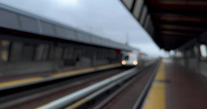 Defocused footage of a municipal train pulling into a station, and of the train pulling out. The video shows themes of public transportation and rail infrastructure, but the bokeh adds abstraction.