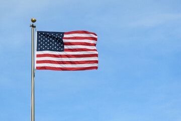 United States stars and stripes flag stretched in wind against blue sky