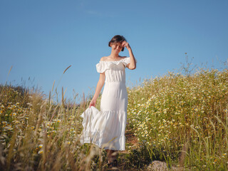 Obraz premium Beautiful Asian young woman in white dress outdoor in flower field. embracing fresh air and engaging in outdoor activities. Friluftsliv concept means spending as much time outdoors as possible
