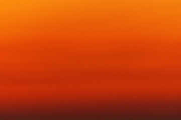 Orange red defocus shot of gradient sky at sunset over ocean horizon. The color changes from orange...